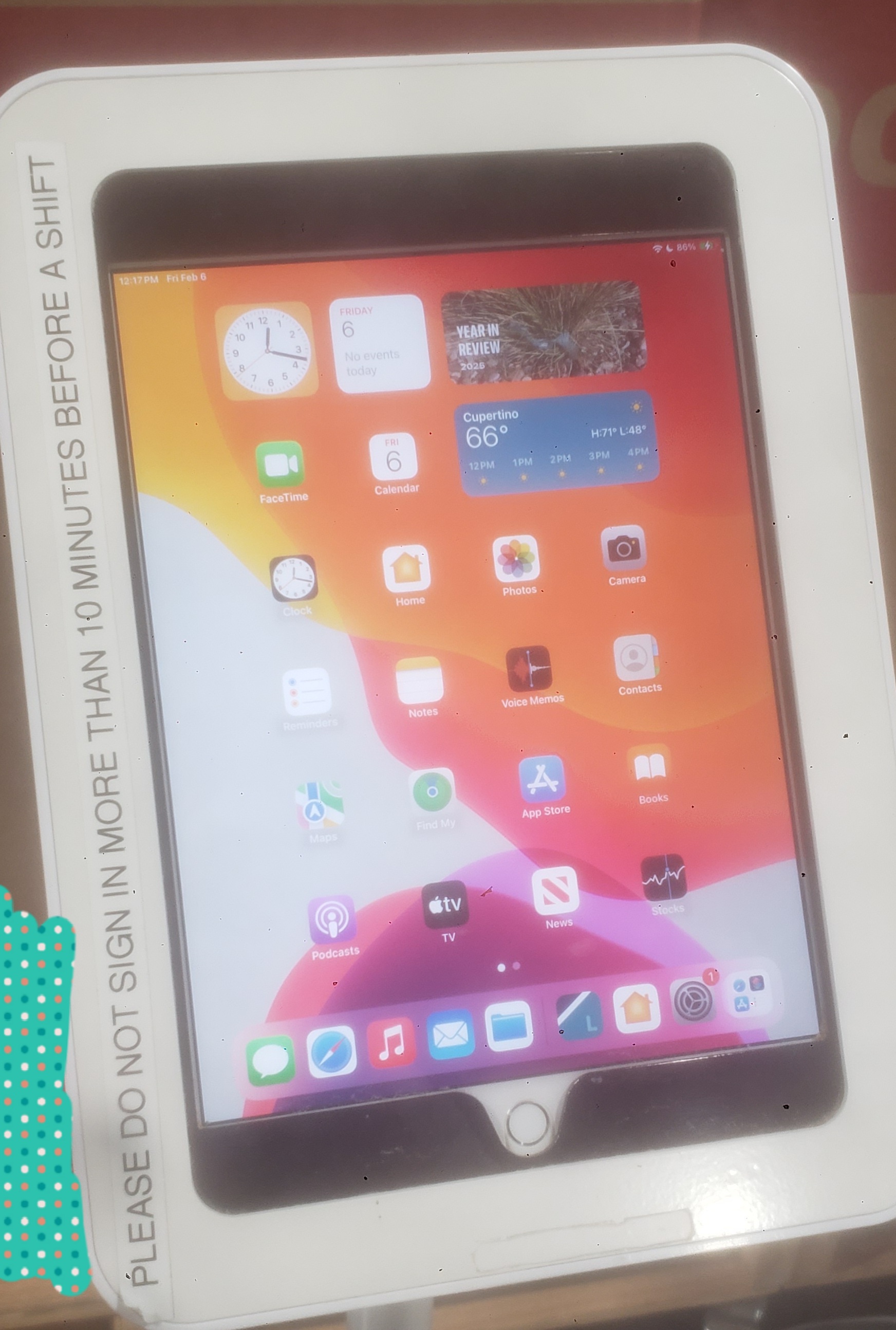 Ipad on the home screen with a sign that says not to sign in more than 10 minutes before your shift.